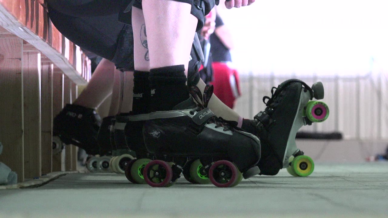 Low view of roller skates lined up beside a wooden barrier.