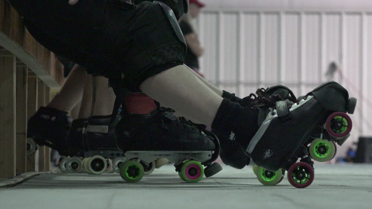 Low-angle close-up of quad roller skates beside a wooden bench.