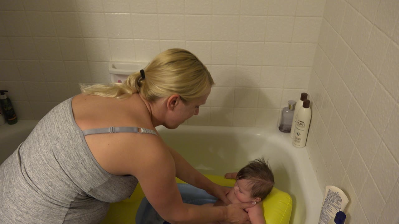 Mother washing infant in baby tub seat