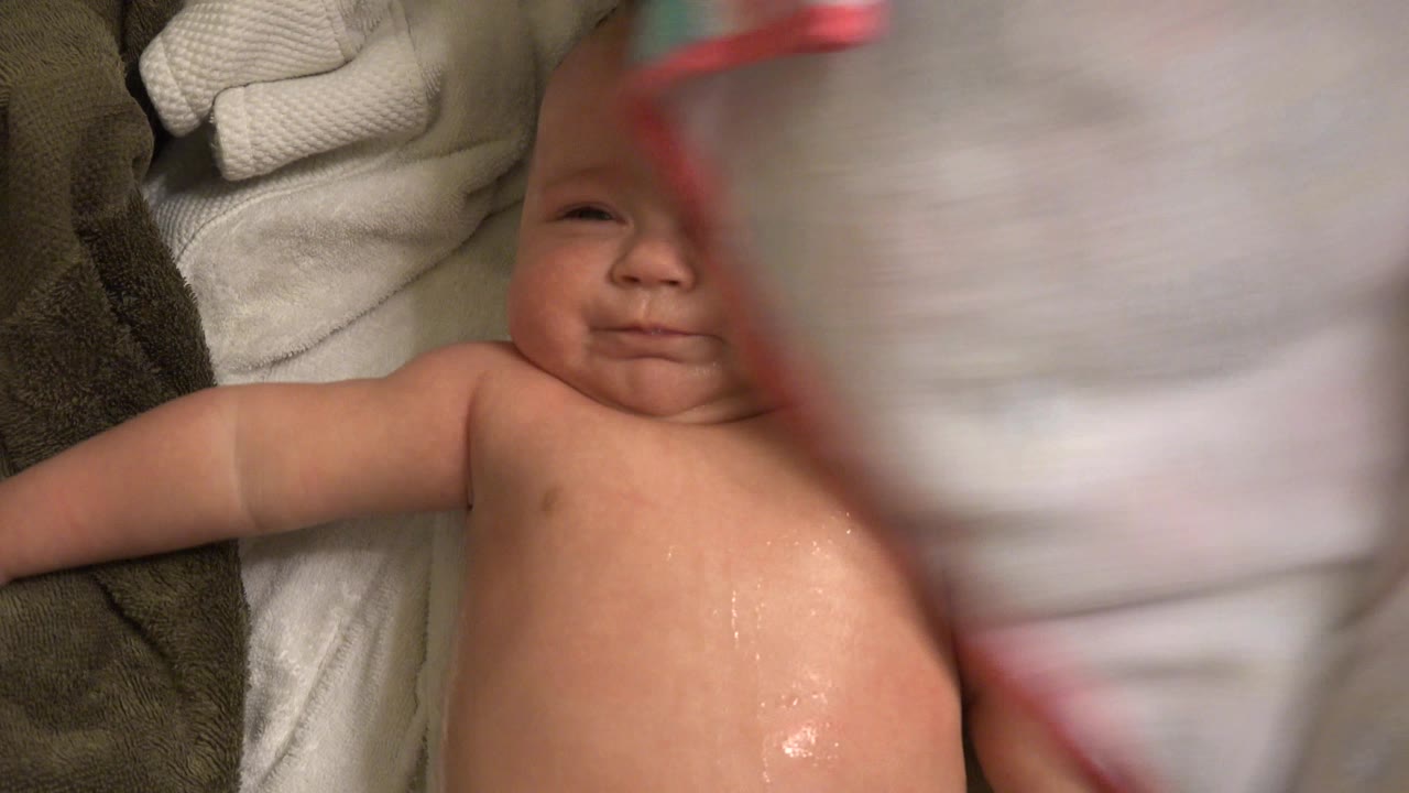 The baby remains lying on towels in Westminster, Colorado, while a large towel obscures the center of the close overhead view.