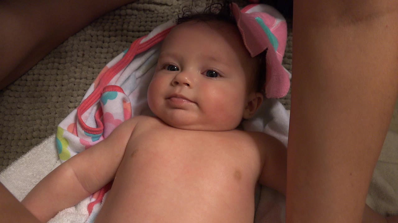 Baby lying on towels with a pink cloth near the head.