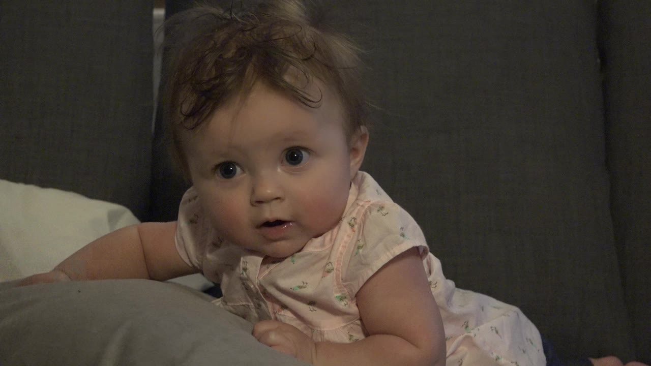 Baby girl looking forward with mouth slightly open.
