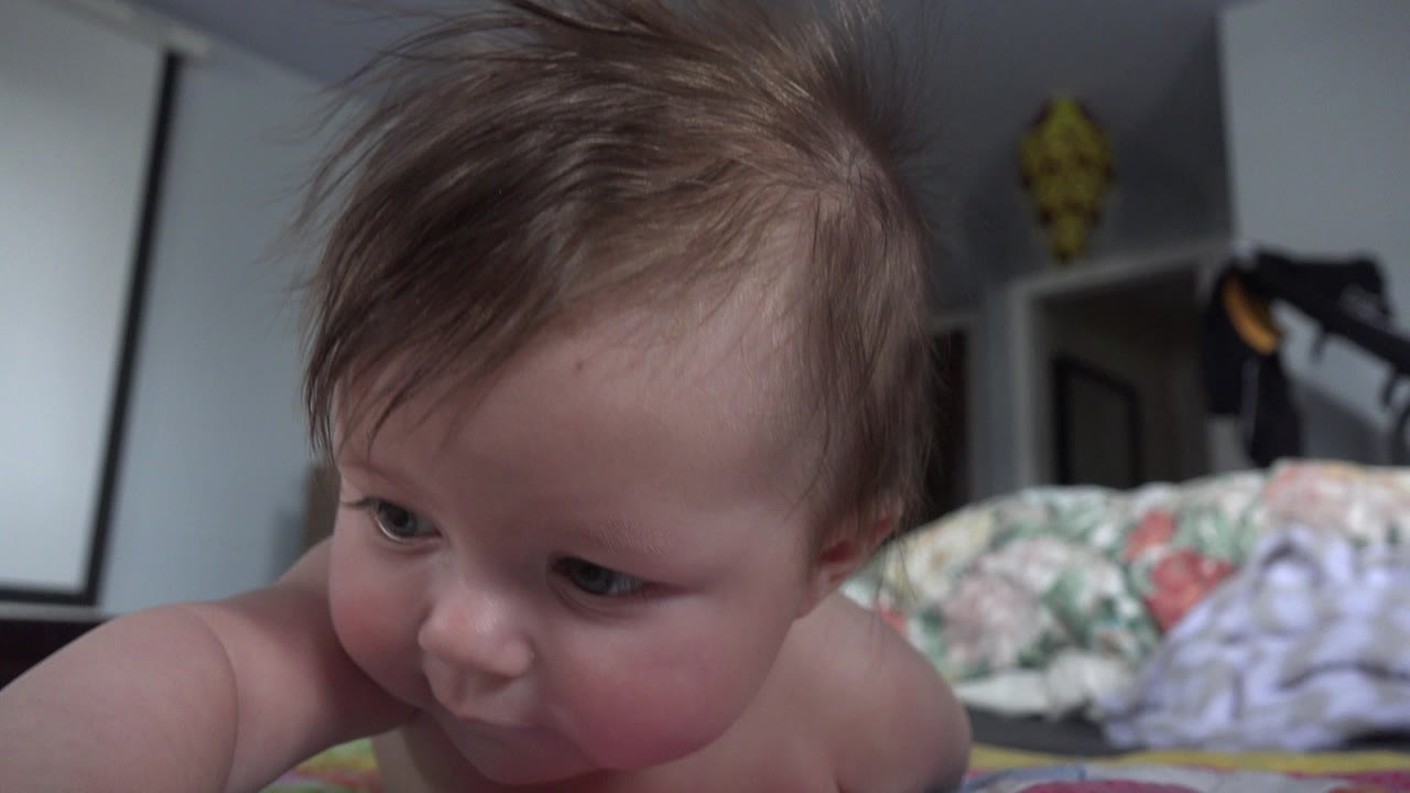 Baby lying close to the camera on a patterned floor blanket.