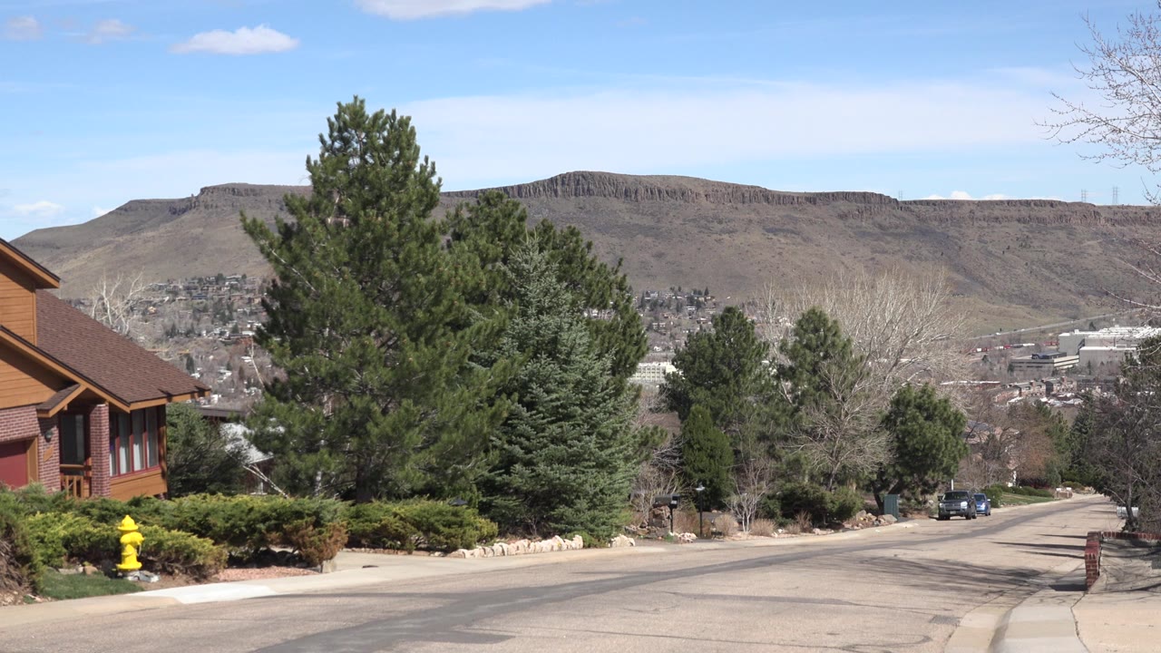 Wide road with trees and a mountain ridge in the distance.