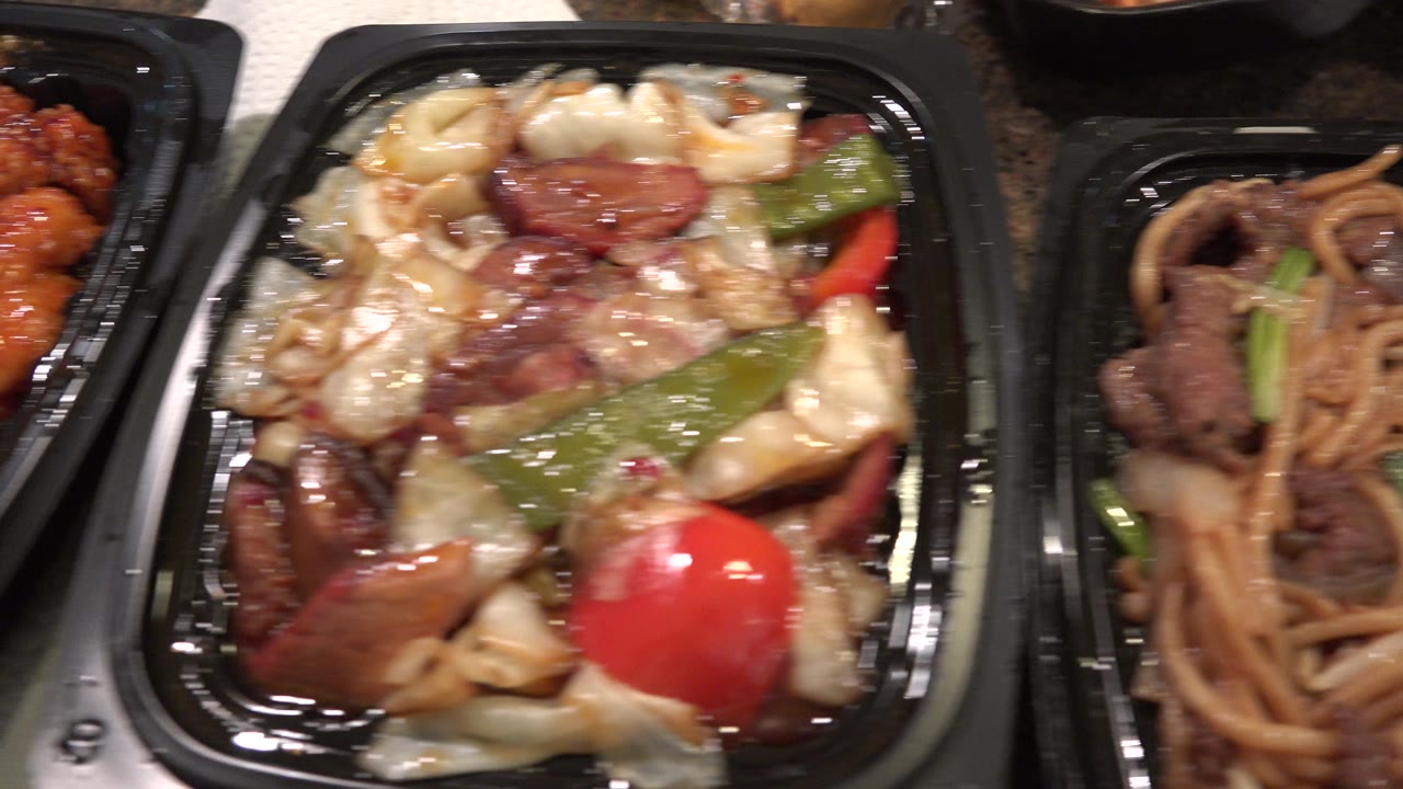 A close food view centers on sauced cabbage, beef, green pepper, and red pepper in a black tray, with a neighboring noodle container along the right edge in Westminster, Colorado, with no visible people.