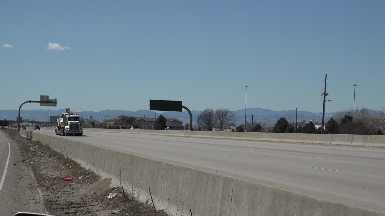 Wide roadway with a distant truck and cars under a blue sky