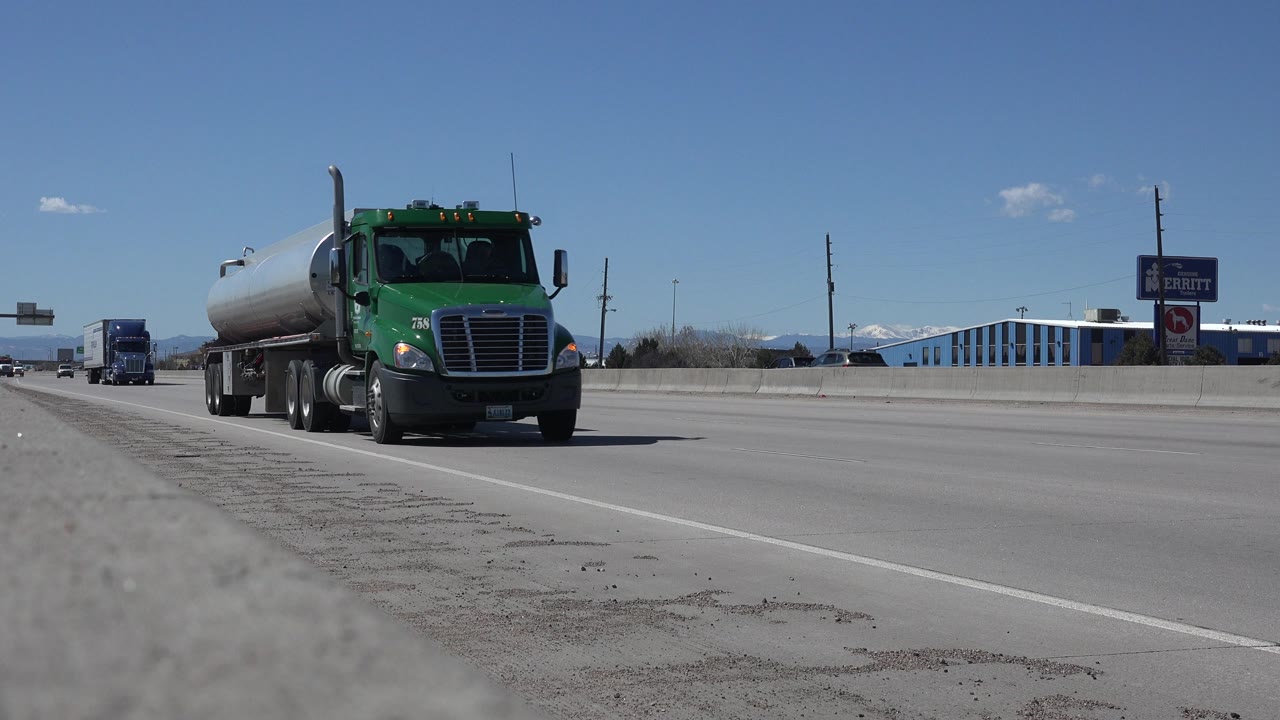 Green tanker truck approaching on a wide highway