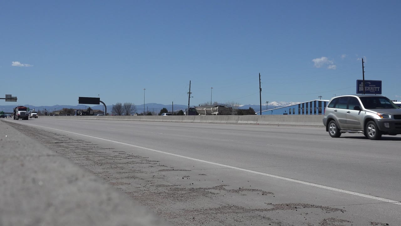 A silver SUV passes close to the right edge of a highway frame.