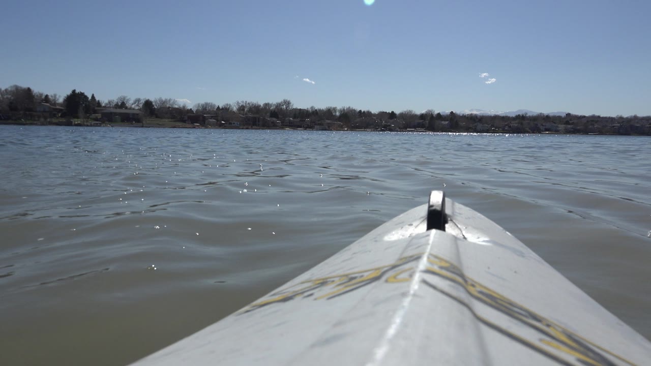 At 0:01, the boat bow stays centered as small waves cross the surface of Hidden Lake, Colorado, with a low wooded shoreline and no visible people.