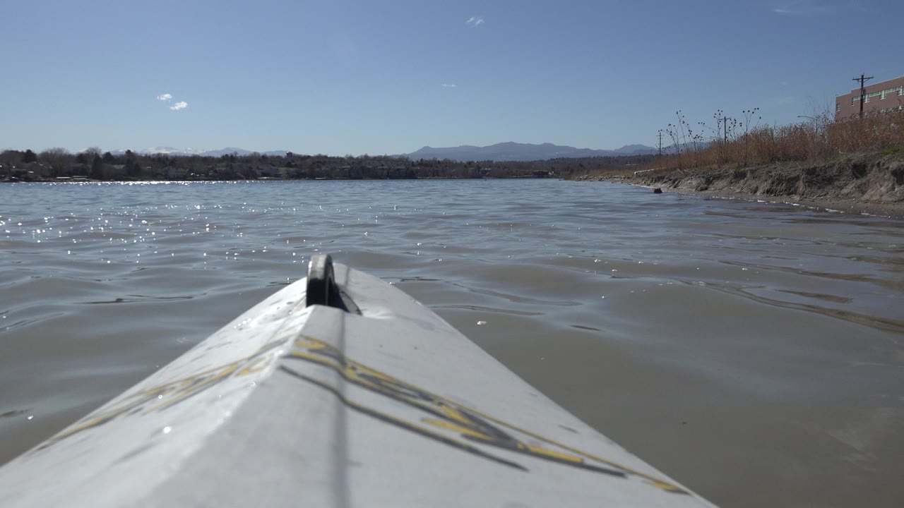 White boat bow on rippling lake water under a blue sky.