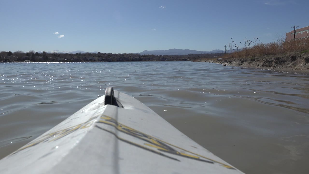 At Hidden Lake Colorado, the boat bow remains centered while small wind ripples cross the lake surface and the far shore stays low on the horizon, with no visible people.