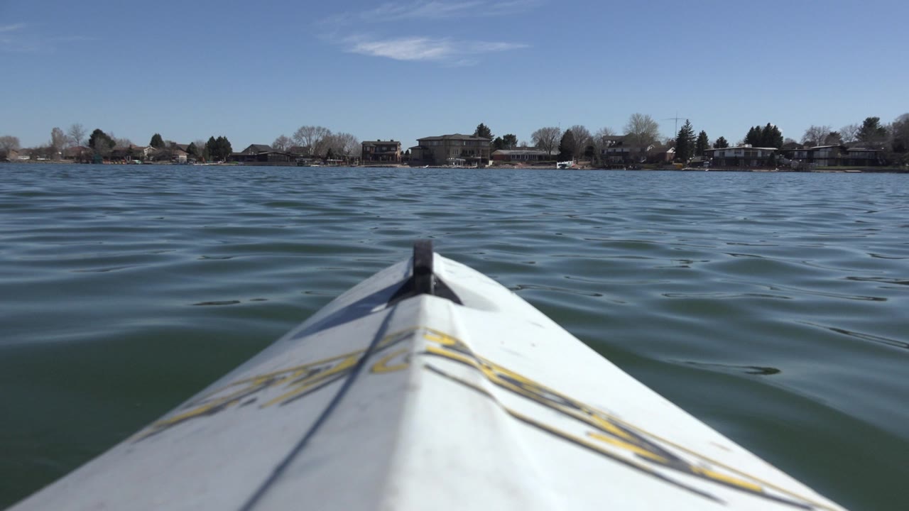White boat bow pointing across rippled lake water toward a distant shoreline.