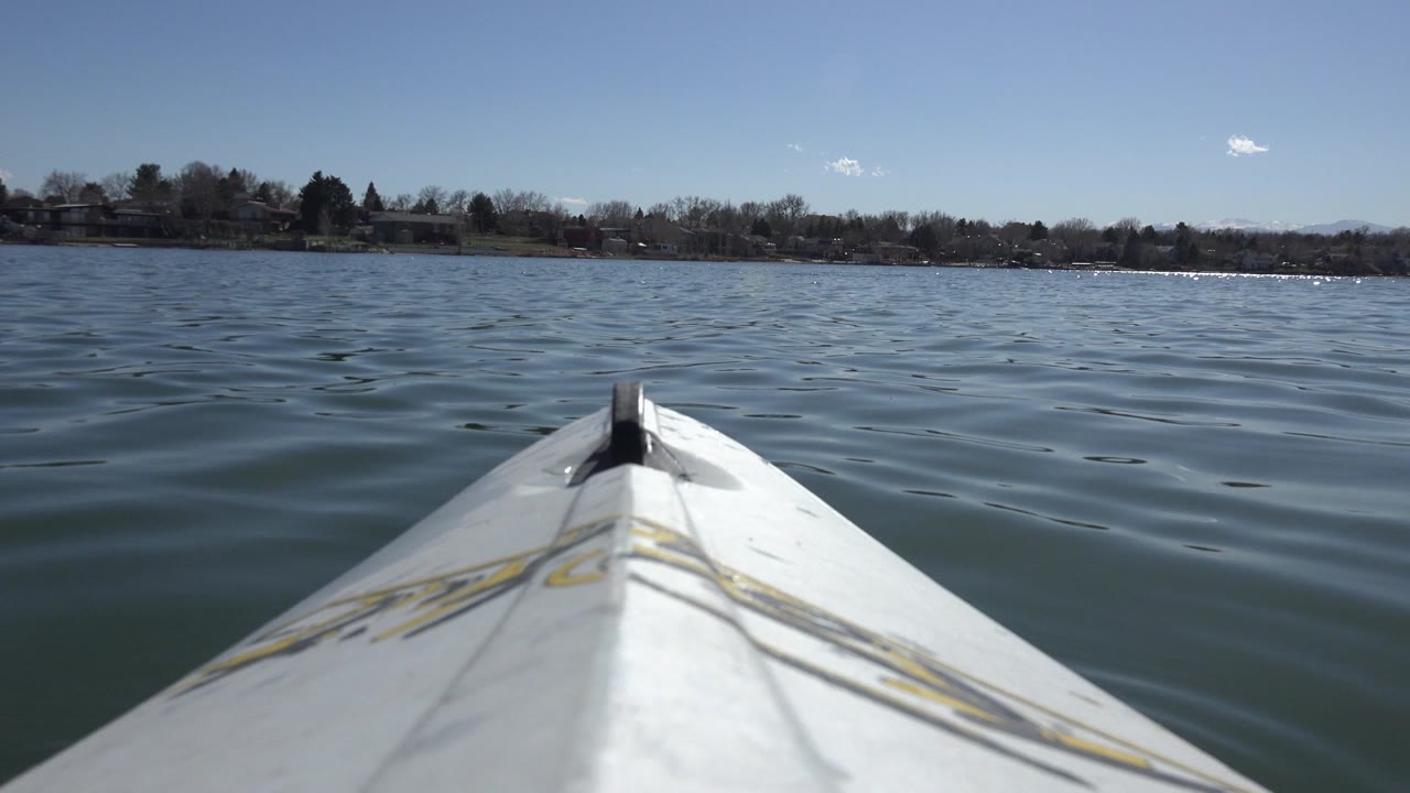 White boat bow pointed across rippled lake water toward a distant shoreline.