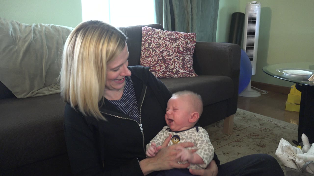 Mother looking down and smiling at baby in her lap.