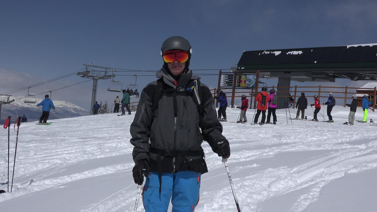 Skier in blue pants standing on snow near a chairlift station.