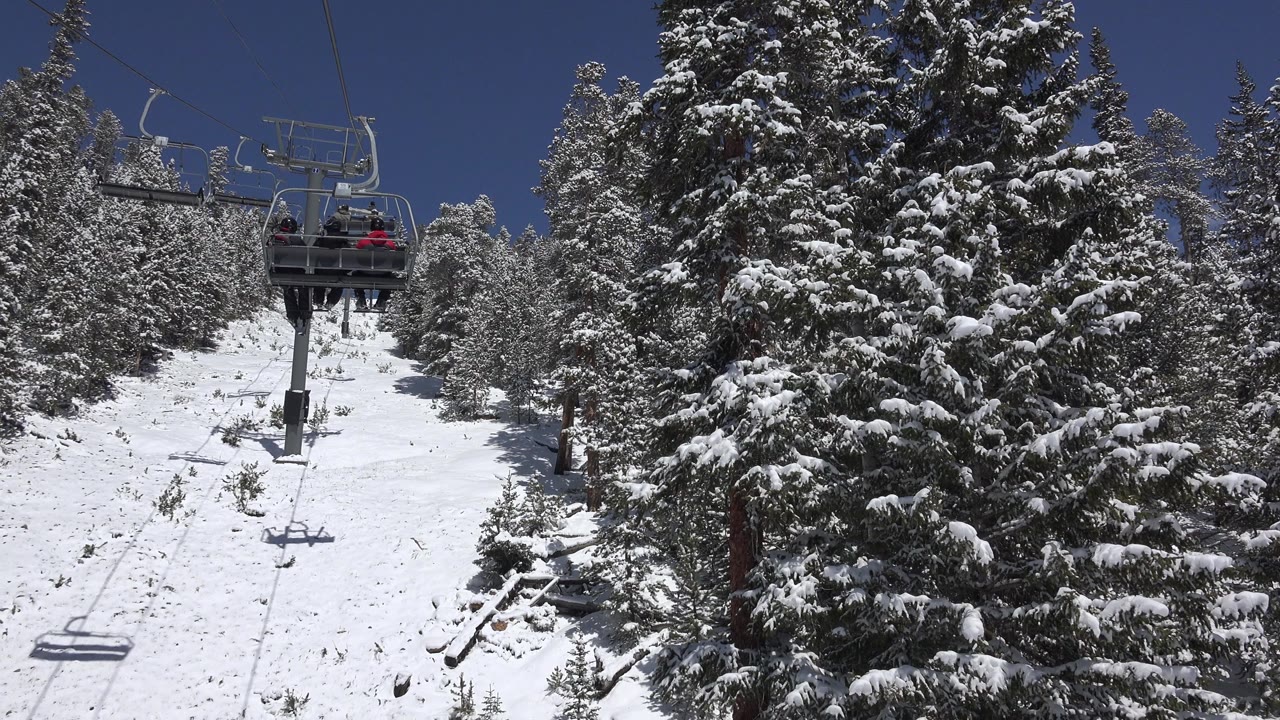 Chairlift over a snowy forested slope.