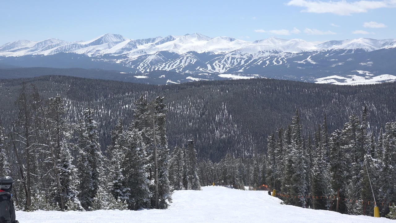 One second into the clip, the Keystone, Colorado view holds on the snow corridor, tall conifers, distant ridgelines, and pale blue sky with no visible people.