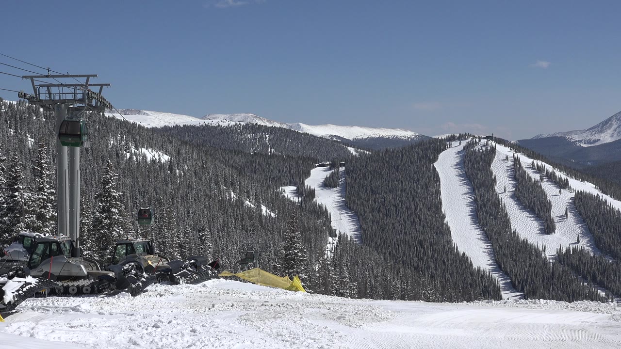 Ski lift tower beside snow-covered forested slopes