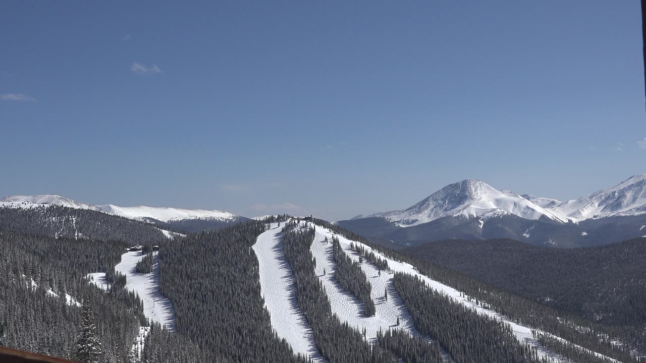 Snowy mountain landscape with forested ridges.