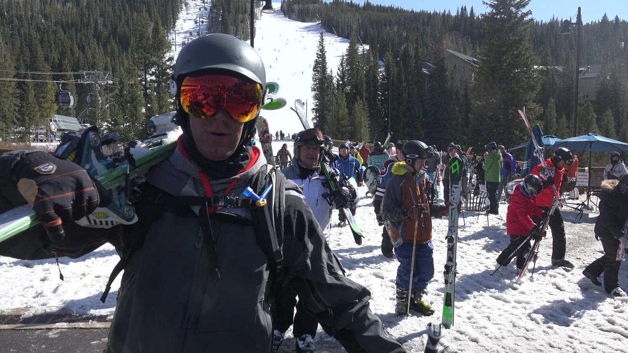 Helmeted skier close to camera at a snowy ski area