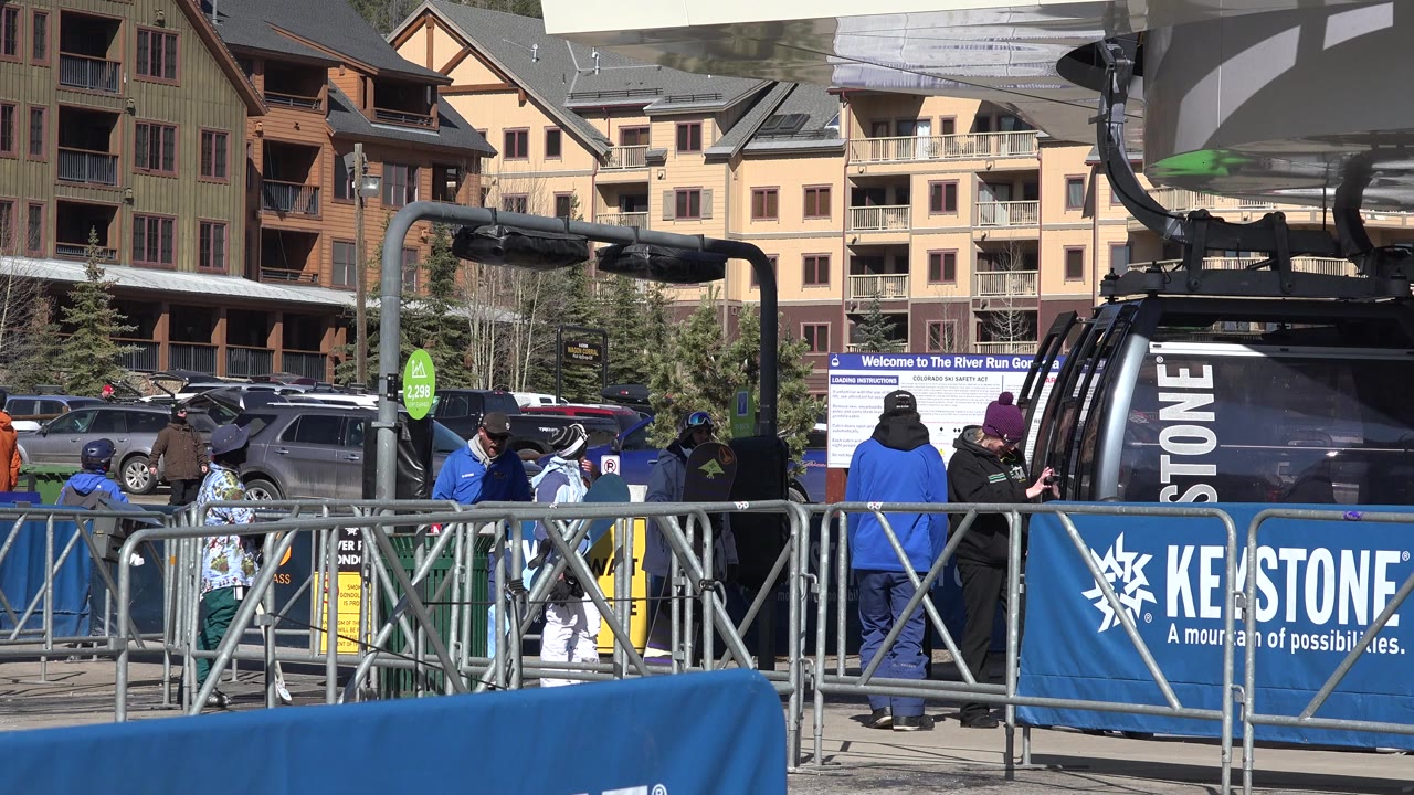 Gondola base with Keystone barrier signage and lodge buildings in sun.