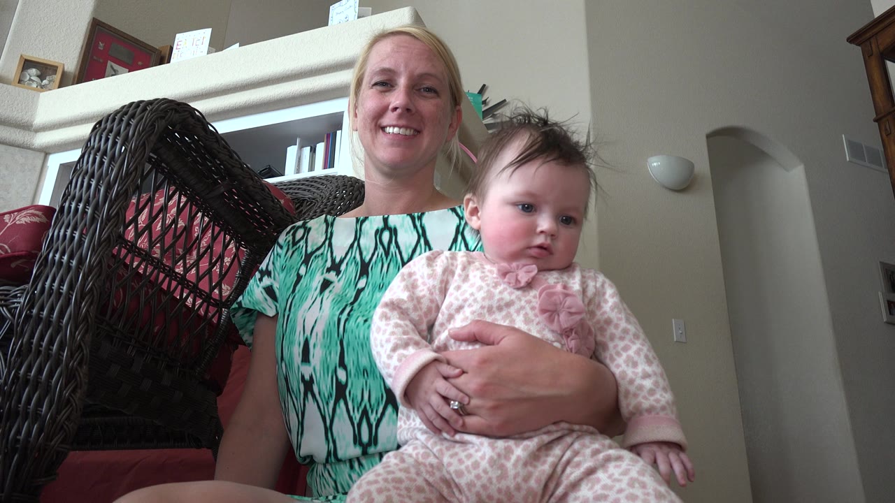The mother smiles toward the low camera while the baby sits on her lap in the Westminster, Colorado home interior.