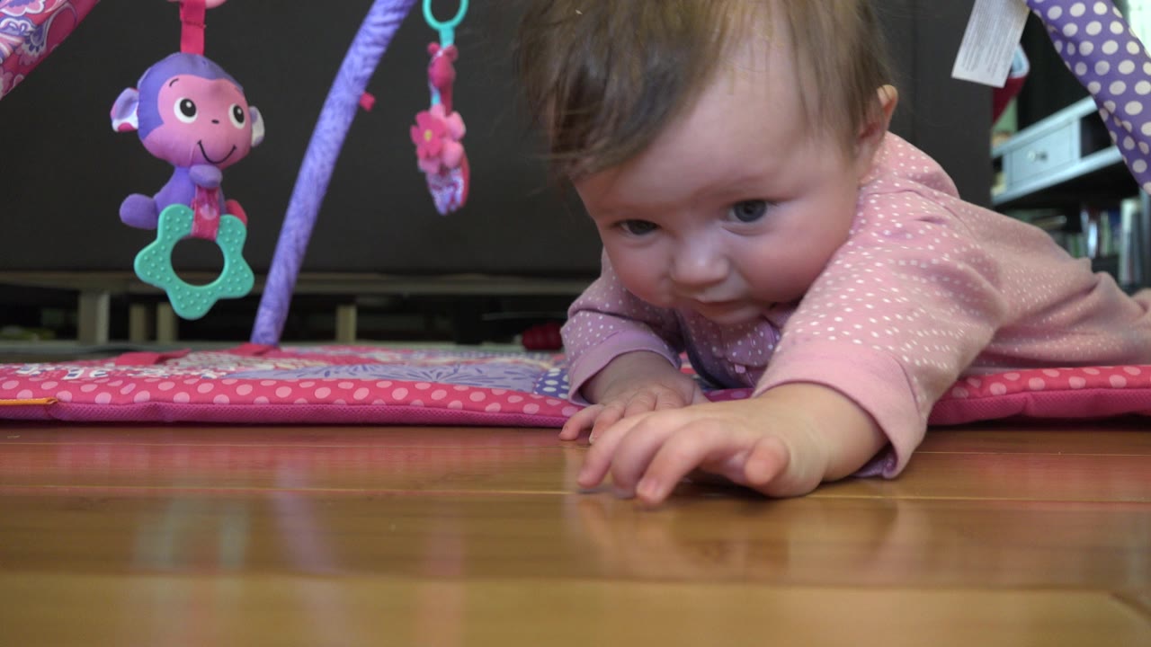 Baby looks forward while reaching with one hand.