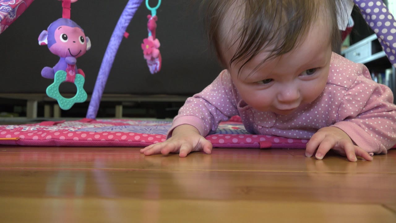 Baby on stomach under a pink play mat