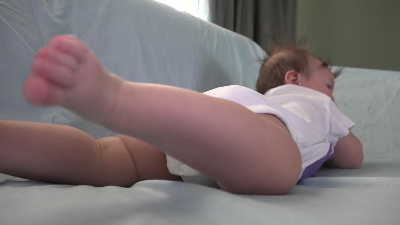 Baby kicking one foot close to the lens while lying on tummy.