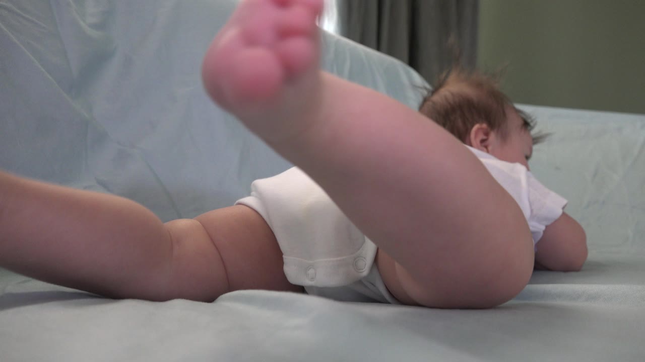 Baby kicking with one leg lifted high on the sofa.
