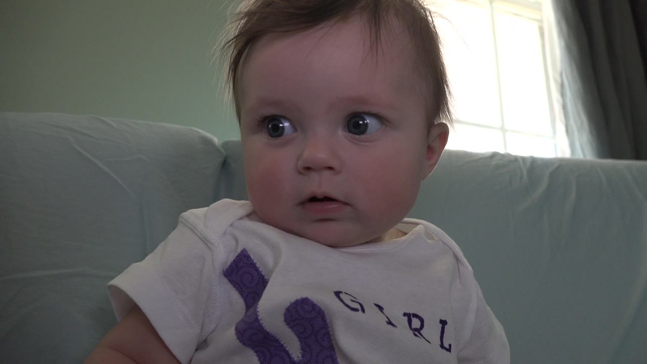 In Westminster, Colorado, the baby remains close in frame and looks slightly off camera, with the pale couch filling most of the background and window light at upper right.