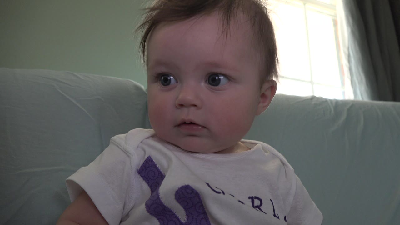 In Westminster, Colorado, the baby turns the gaze farther to the side, showing a more serious expression against the pale couch and bright window background.