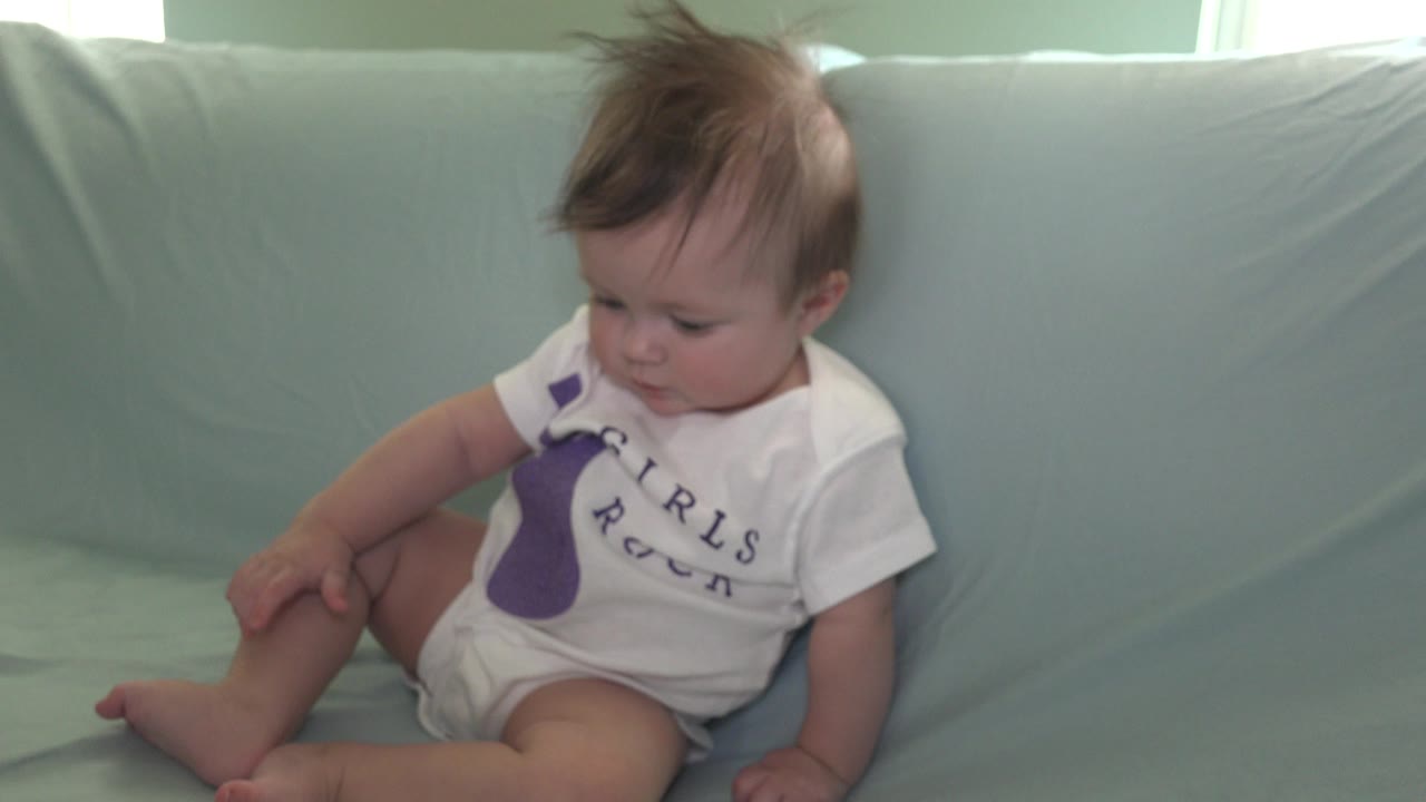 Baby leaning left on a pale blue couch.