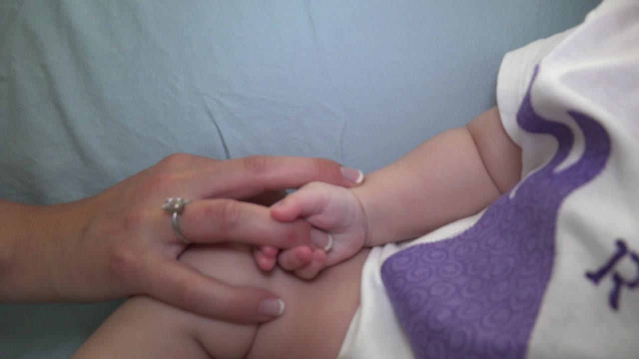 Baby hand holding an adult woman's index finger.