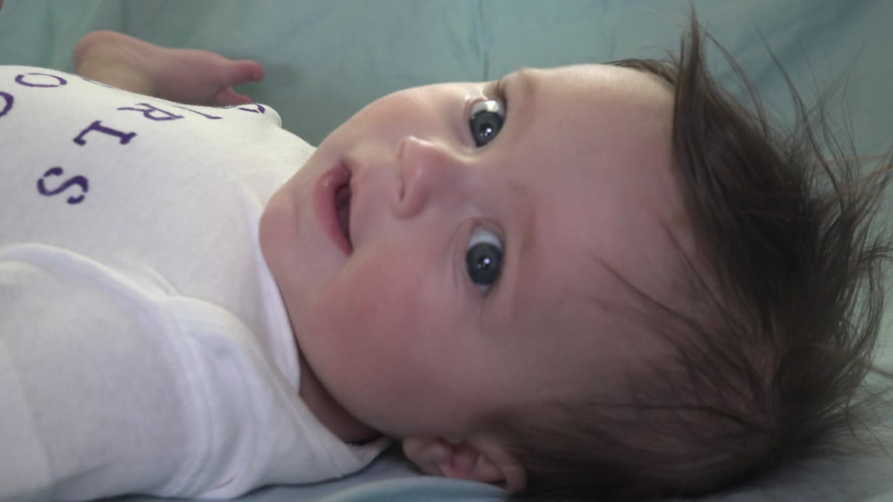 In Westminster, Colorado, the infant remains on the light green blanket, face turned slightly upward with the mouth parted and hair spread above the head.