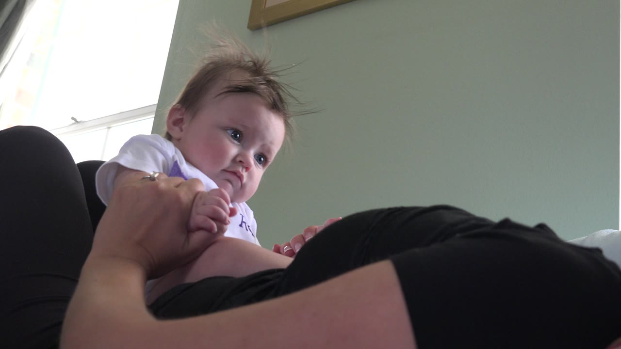 Baby looking to the side while an adult holds them.