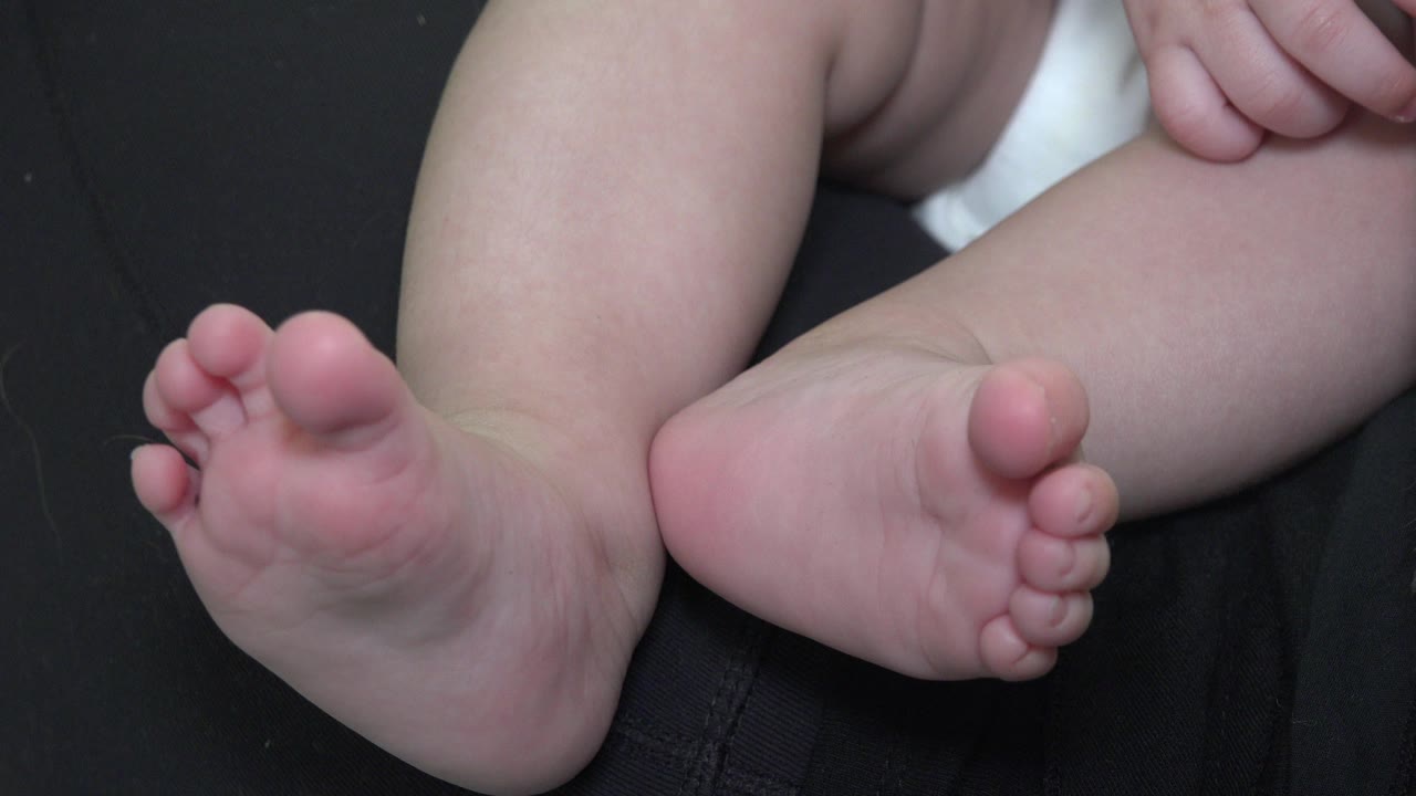Baby feet and legs on dark fabric.