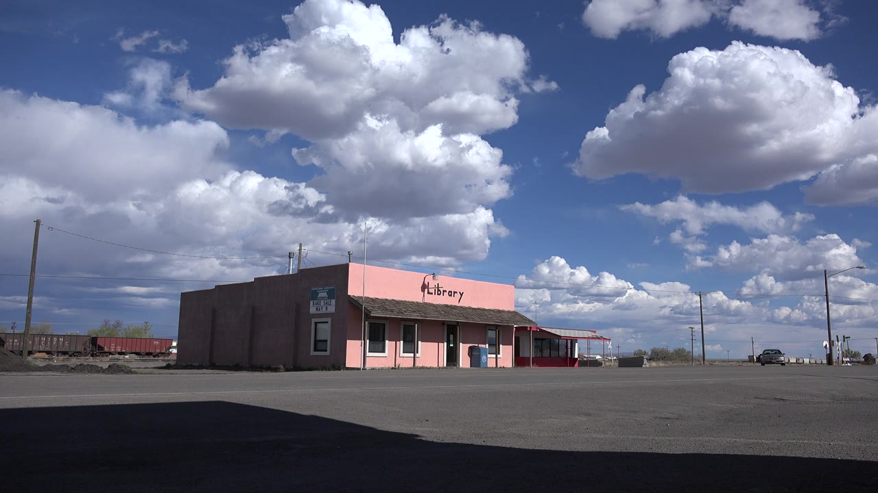 Pink library storefront across a wide road under large clouds.