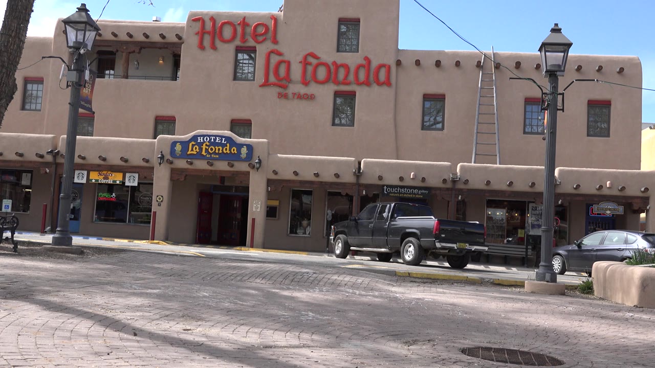 Hotel entrance and red facade sign beside street lamps.