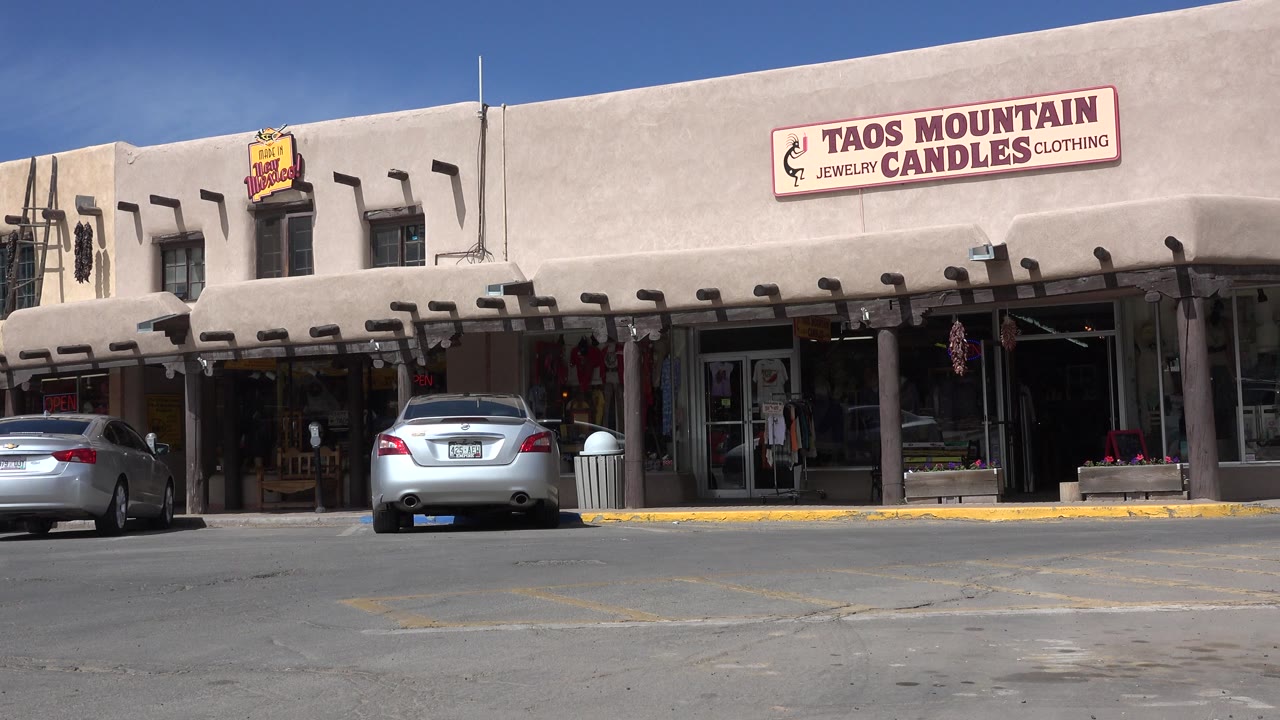 Tan commercial storefront with Taos Mountain Candles sign and parked cars