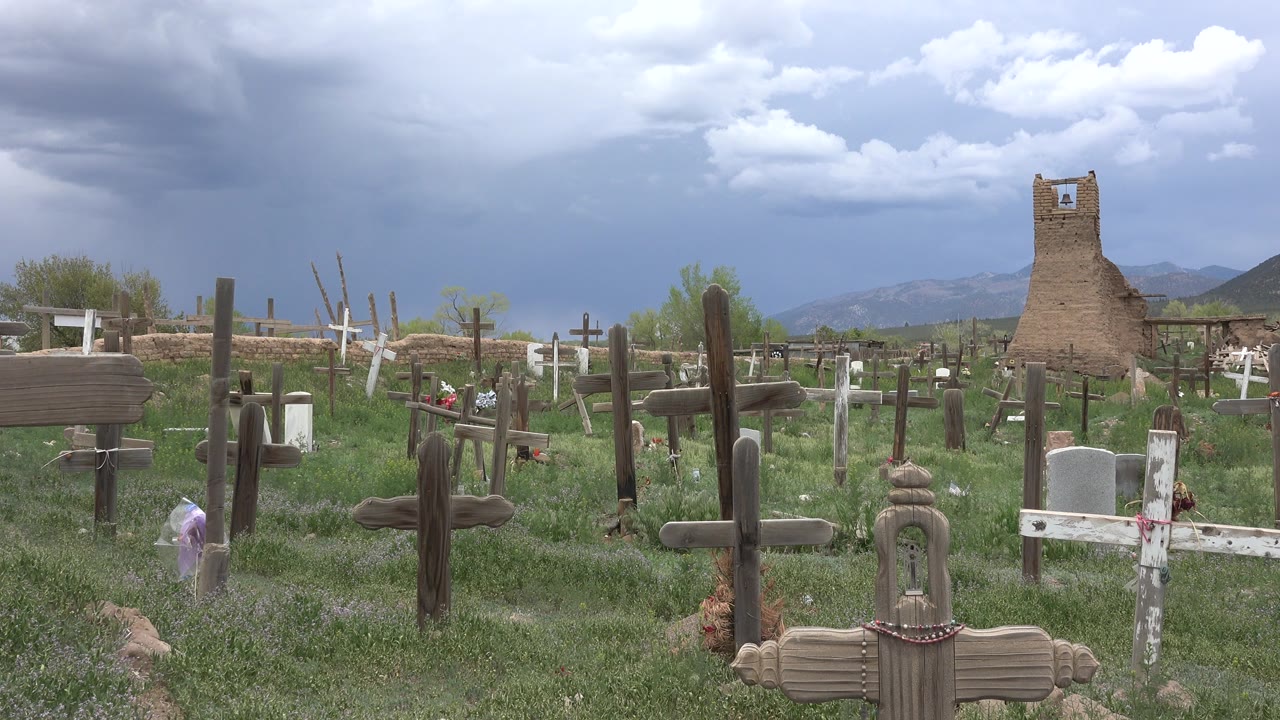 Christian cemetery with crosses in green grass under storm clouds