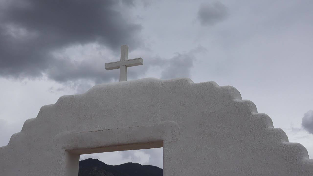 White church top with cross and dark clouds