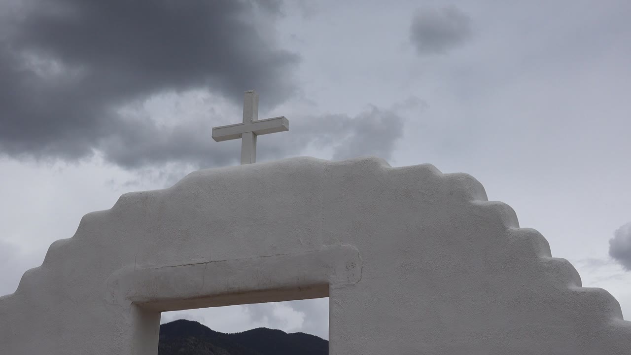 Church-like white wall with cross and cloudy sky