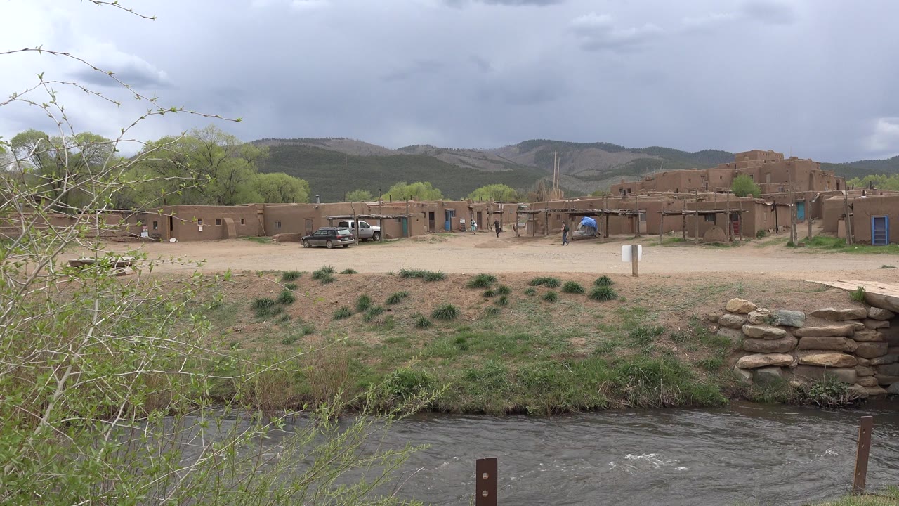 Creek in front of tan buildings under a cloudy sky.