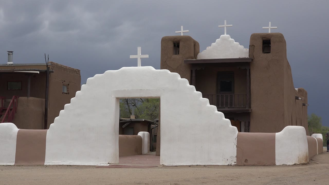 White stepped church entrance with crosses under a cloudy sky.