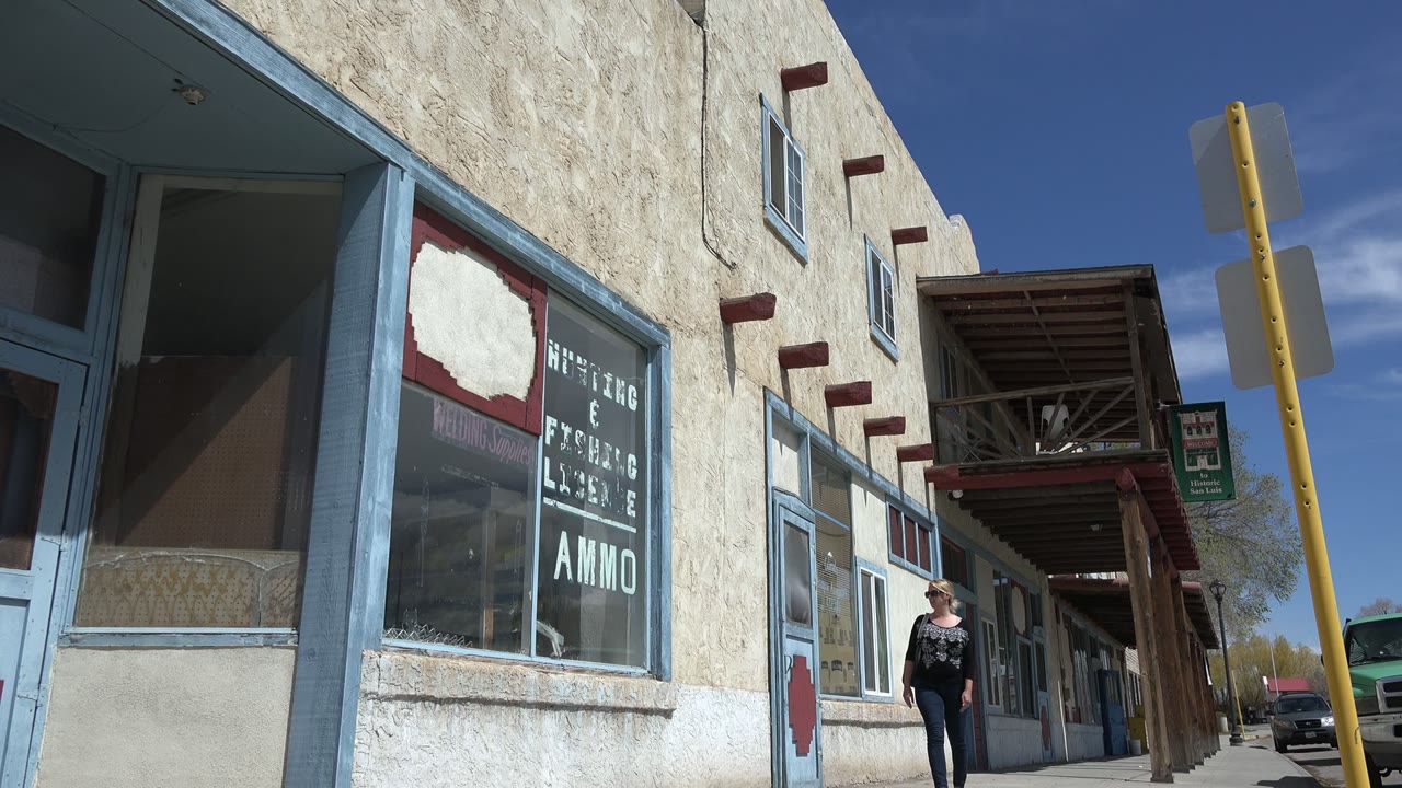 Woman walking under storefront awning with yellow signpost nearby