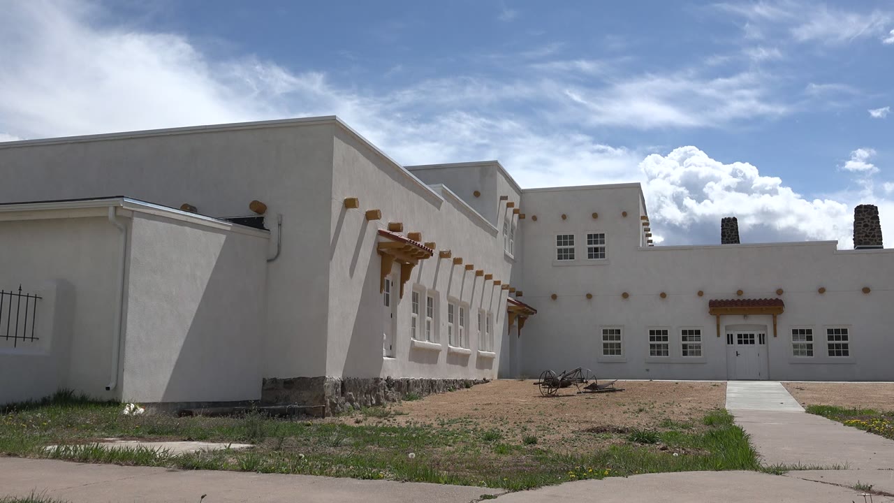 White stucco building exterior with walkway and blue sky.
