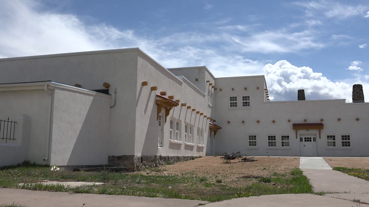 White building exterior beside sidewalk under blue sky