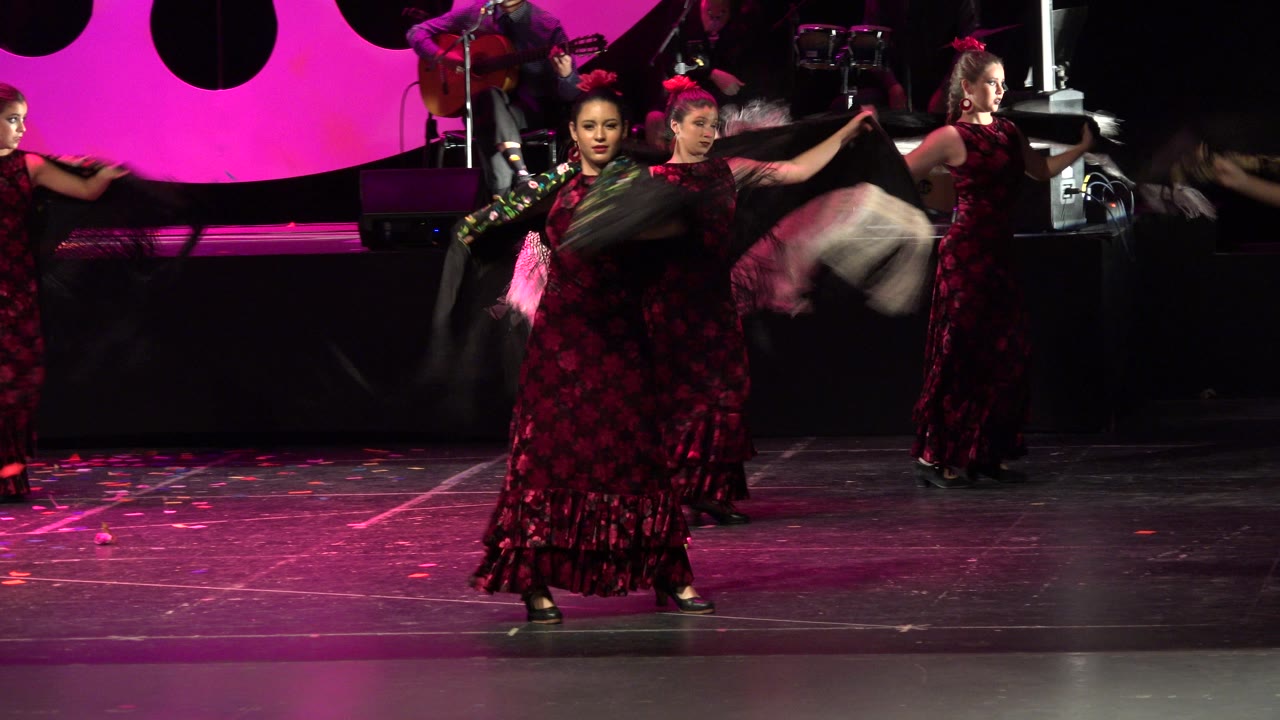 Three dancers hold shawls wide across a dark stage.