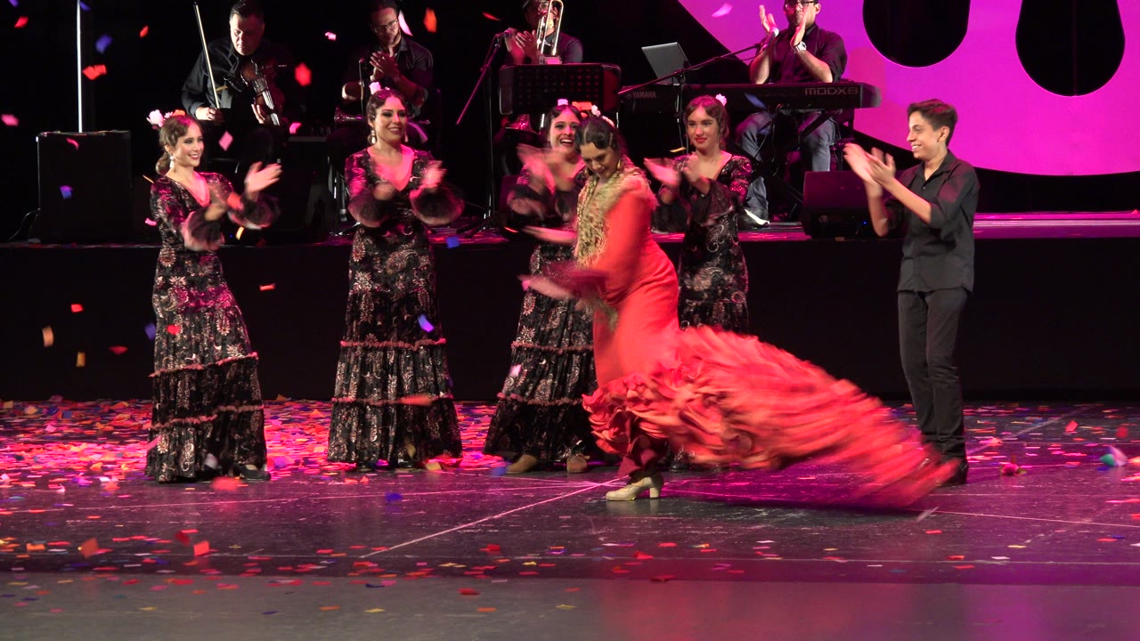 One second in, the Cabo San Lucas stage dancer sweeps the red dress low across the floor as confetti falls and the clapping performers remain lined up beside her.